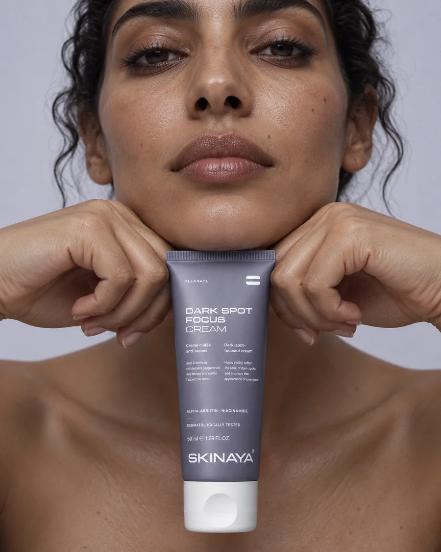 A woman resting her chin on her hands with the MELANAYA Dark Spot Focus Cream tube